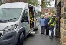 Minibus driver and 2 passengers standing next to minibus grey in colour.