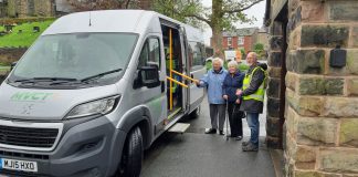 Minibus driver and 2 passengers standing next to minibus grey in colour.